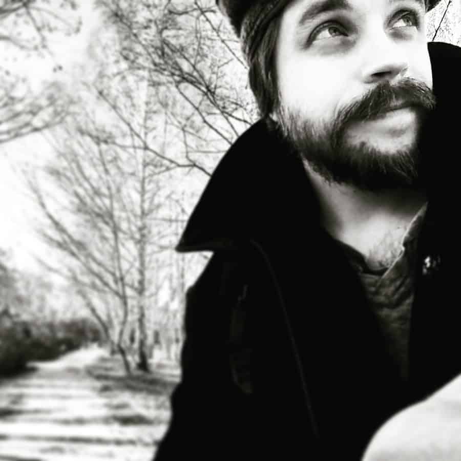 The vintage-style image captures the emotional depth of the man with a thoughtful gaze amidst nature.