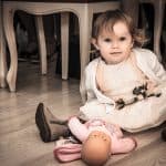 The vintage-style photo captures the emotional moment of the baby girl sitting on the floor with her.