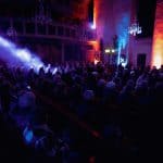 The vintage-style concert hall is bathed in purple and orange lights, creating an emotional atmosphe.