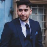 The image captures the emotional depth of a man dressed in a vintage-style navy suit, standing outdo.