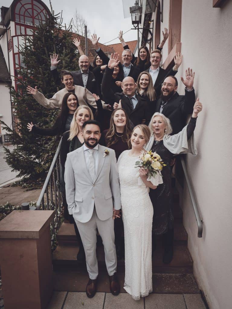 The vintage-inspired wedding photo shows the bride and groom surrounded by friends and family, all celebrating love and unity in a warm, nostalgic atm.