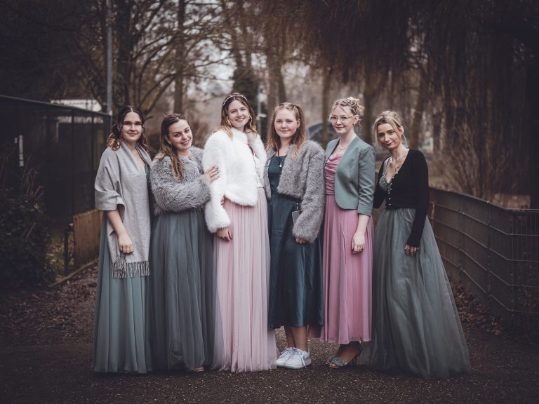 A group of women dressed in vintage-style gowns standing outdoors, showcasing timeless fashion and joyful camaraderie.